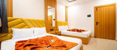 Quarto de hotel com duas camas, um espelho grande e um guarda-roupa de madeira.