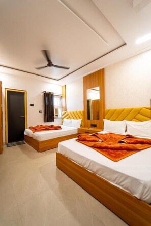 Habitación de hotel con dos camas, un ventilador de techo, un espejo y una puerta.