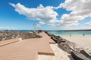 A wooden boardwalk leading to a sandy beach with a clear sky and a few clouds. - Home2Book Betty Modern Studio in Puerto (Puerto del Rosario)