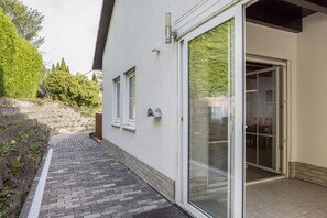 A residential building with a paved pathway leading to a glass door entrance. - Apartment 'Unterhaun' with Private Garden and Wi-Fi (Hauneck)