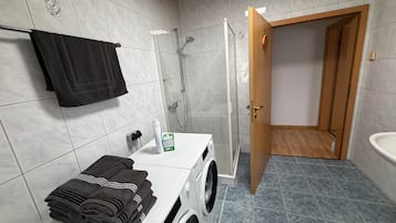 Une salle de bain équipée d’un lave-linge, d’un porte-serviettes et d’une douche.