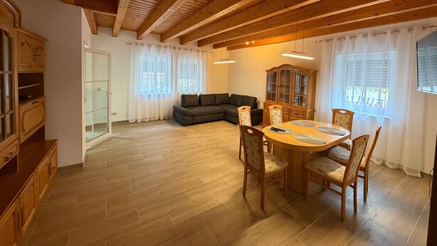 Un vaste espace de vie doté d’un plafond en bois, d’un canapé, d’une table à manger avec des chaises et d’un meuble.