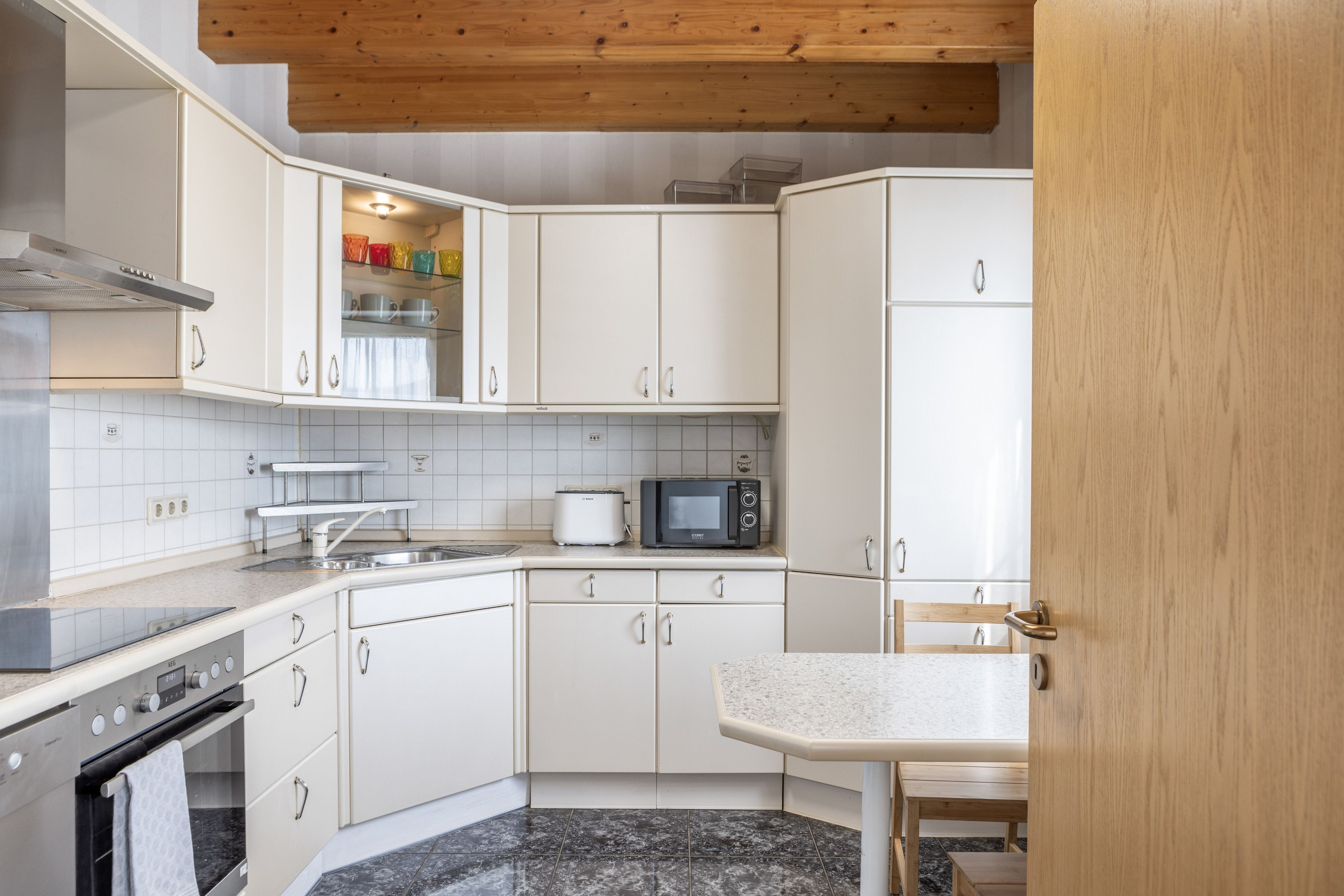 A modern kitchen with white cabinets, a microwave, a toaster, and a sink.