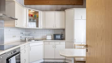 A modern kitchen with white cabinets, a microwave, a toaster, and a sink.