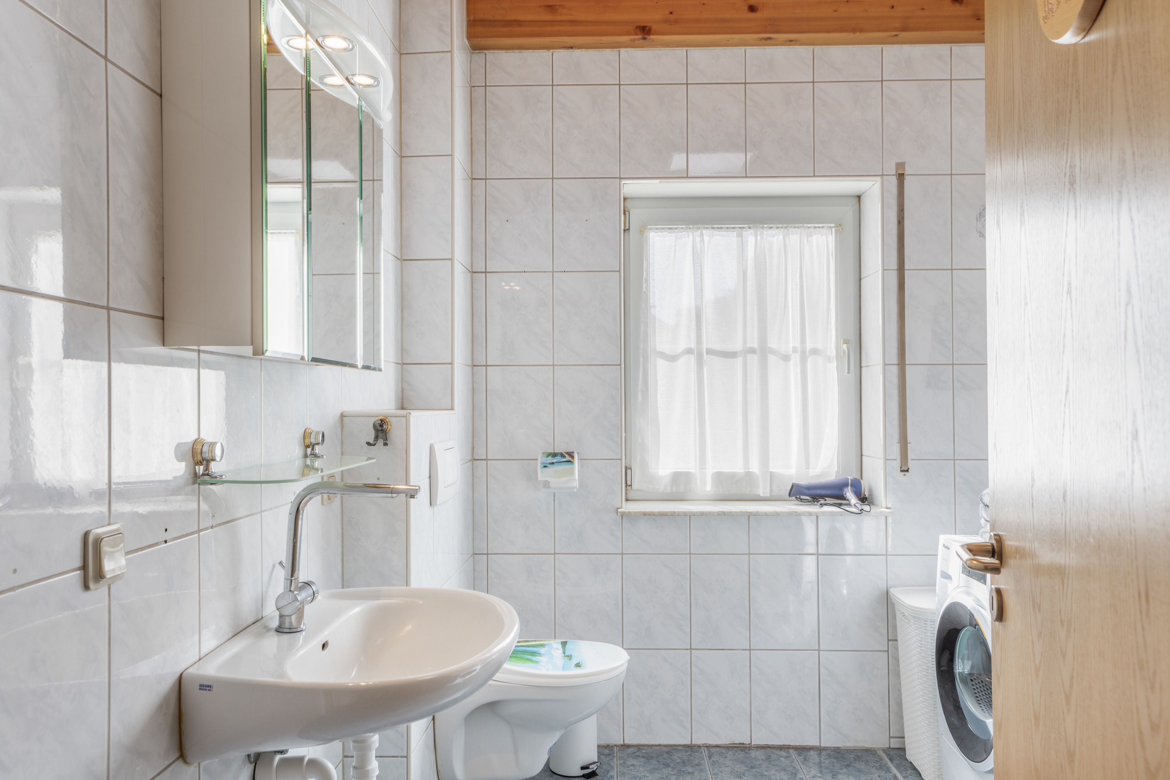 Un baño con lavamanos, inodoro y lavadora.