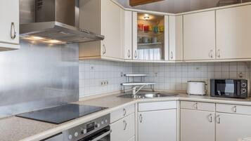 Une cuisine avec des armoires blanches, une hotte de cuisinière en acier inoxydable, un four à micro-ondes Bosch et un grille-pain Bosch.