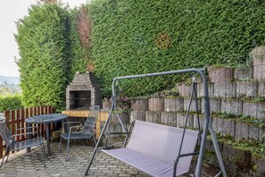 A patio area with a swing set, a round table, and a grill. - Apartment 'Unterhaun' with Private Garden and Wi-Fi (Hauneck)