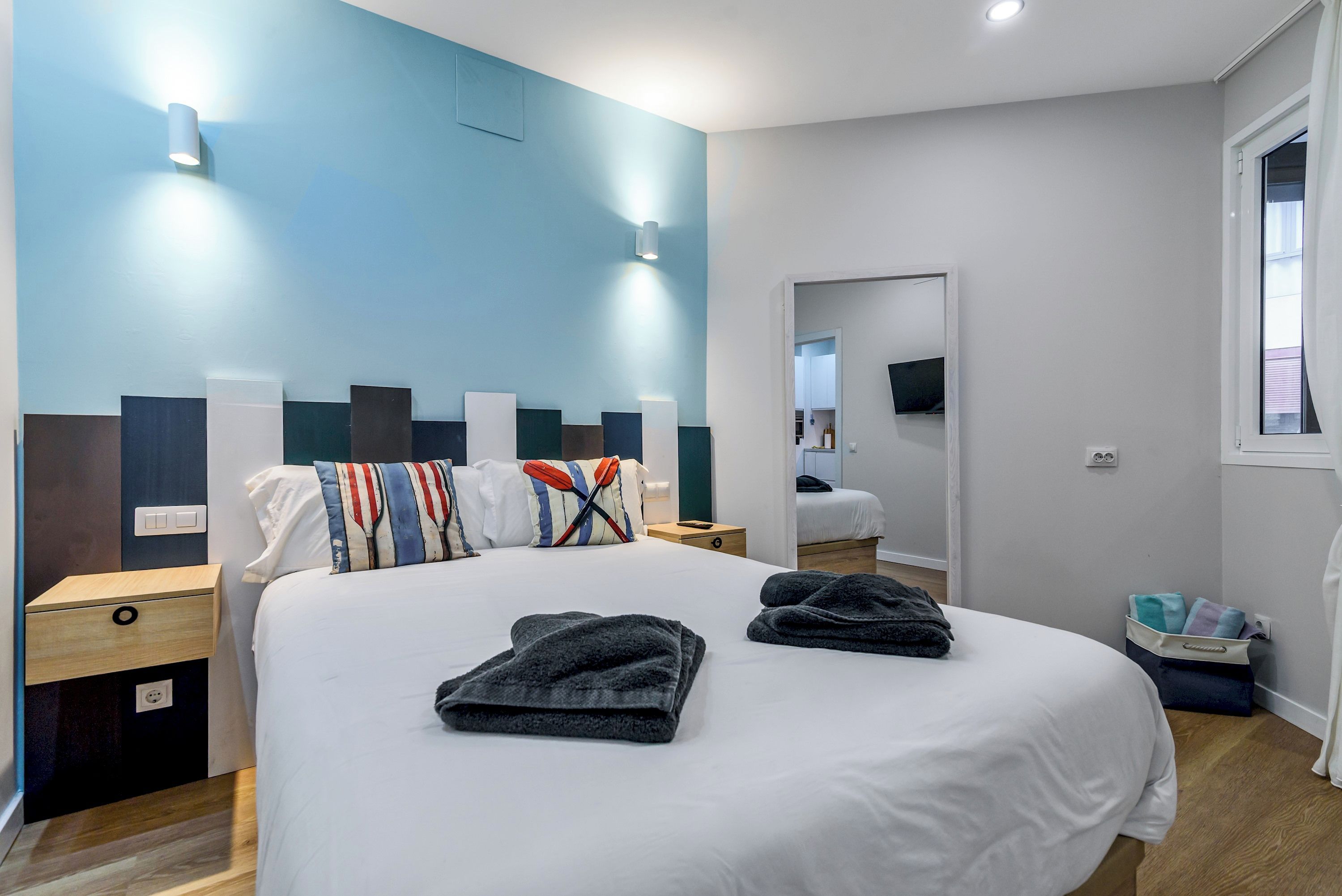 Un dormitorio moderno con una cama grande, mesitas de noche, un televisor de pantalla plana y un ventanal.