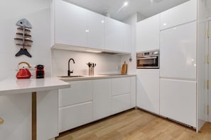 A modern kitchen with white cabinetry, a stainless steel sink, and a built-in oven. - Home2Book El Faro by Las Canteras Beach (Las Palmas de Gran Canaria)