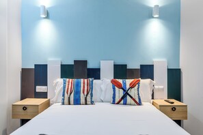 Ein Hotelzimmer mit einem Bett, zwei Nachttischen und einer Wand in Blau-Weiß.