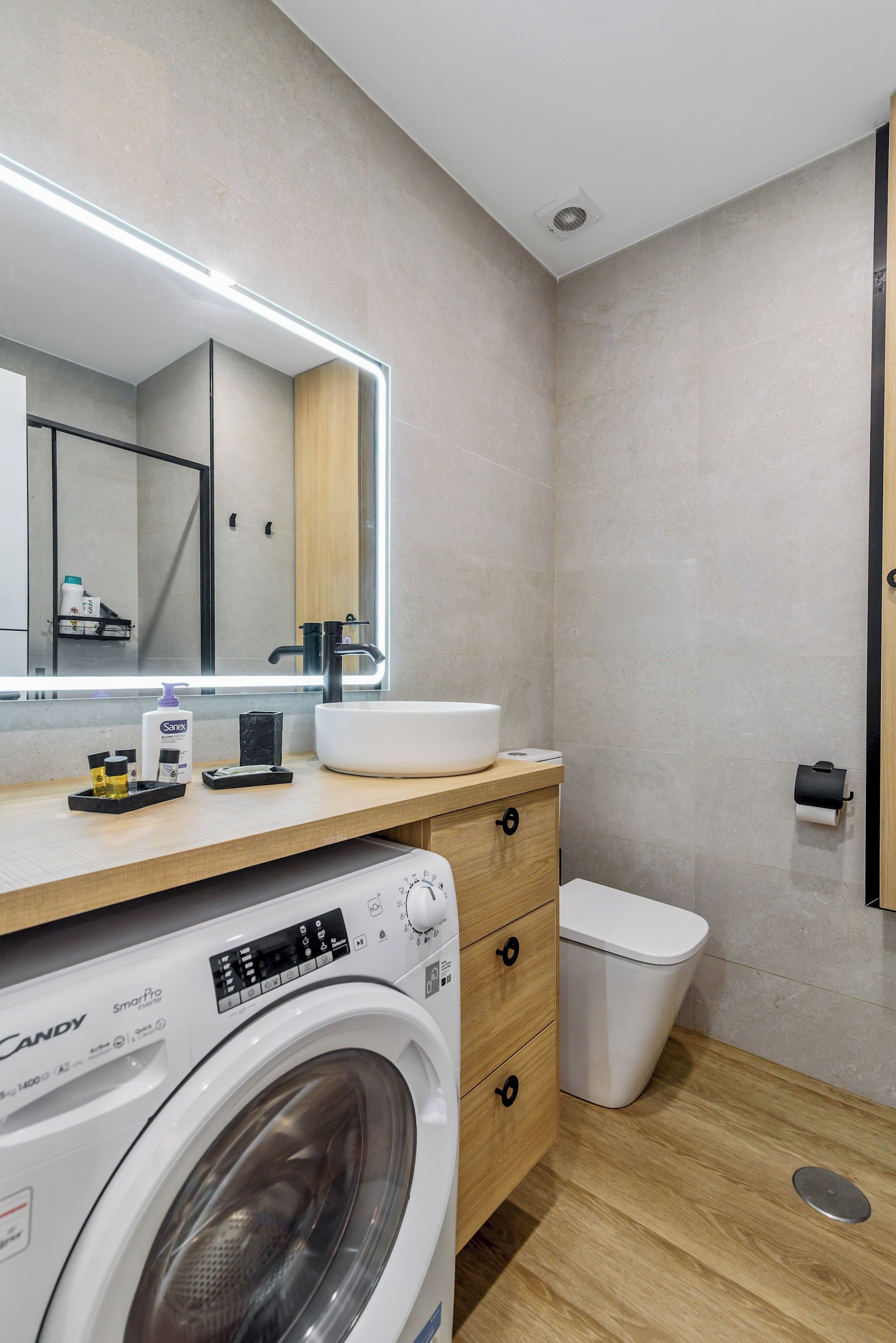 A modern bathroom with a built-in washing machine, a sink, and a toilet.