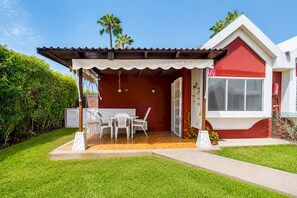 A house with a patio, a dining area with chairs, a small table, and a red and white exterior. - Home2Book Los Tunos Bungalow & Pool, Maspalomas (Maspalomas)