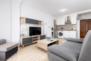 Ein modernes Wohnzimmer mit einem Flachbildfernseher, einem Couchtisch und grauen Sofas.