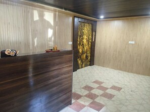 A room with a reception desk, a decorative golden statue, and a patterned floor. - Beas Heaven Hotel And Cafe (Kullu)