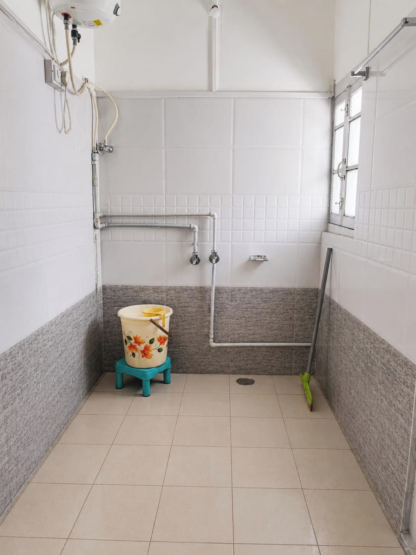 A bathroom with a toilet, shower, and a window.