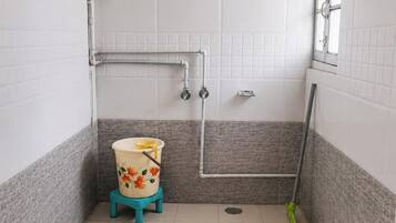 A bathroom with a toilet, shower, and a window.