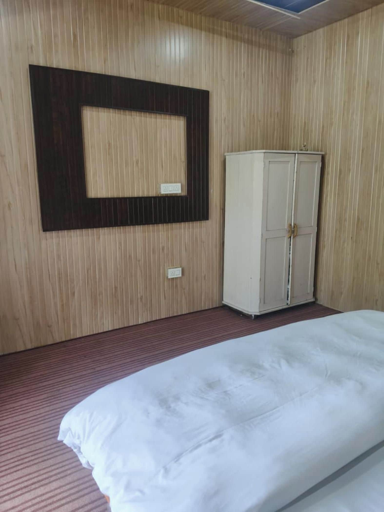 A room with a bed, a wardrobe, and a wall-mounted TV.