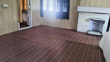 Una habitación con alfombra estampada, chimenea y ventana con cortinas.
