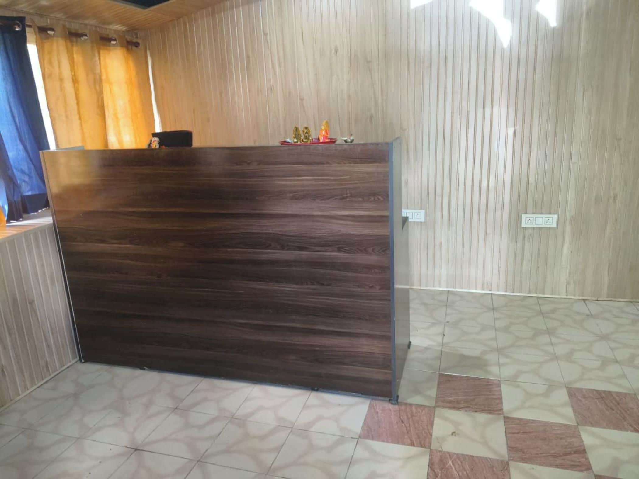 Ein Empfangsbereich mit dunklem Holzdesign, einem gemusterten Boden und einer hellen Wand mit vertikalen Linien.