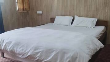 Una cama individual con ropa blanca en una habitación con paredes de madera y alfombra a rayas.