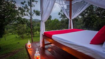 A bed with a canopy, a bench, and lanterns in a forested area.