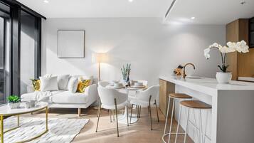 Una sala de estar moderna con un sofá, sillas, una mesa de centro y un comedor con una mesa y sillas.