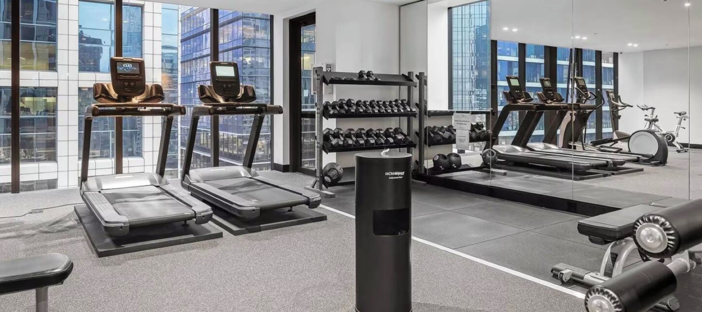 Une salle de sport moderne équipée de tapis de course, d’appareils de musculation et d’une variété de poids.