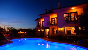 A two-story building with a swimming pool, outdoor seating, and a bar area.