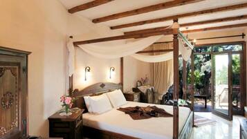 A bedroom with a four-poster bed, a nightstand, a dresser, and a window with curtains.