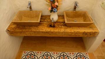 A bathroom with two wooden sinks, a white vase with flowers, and a patterned tile floor.