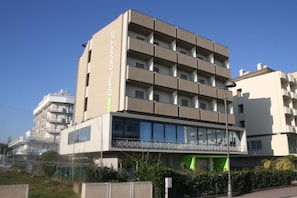 Um edifício moderno com vários andares, com varandas e entrada no nível da rua.