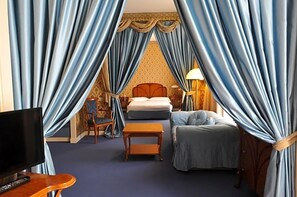 A hotel room with a bed, a TV, a small table, and a chair. - Hotel Astoria (Grado)