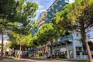 A hotel with a modern architectural design, featuring balconies and a central courtyard with trees. - Hotel Astoria (Grado)