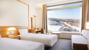 A hotel room with two beds, a desk, a chair, and a large window with a view of a snowy landscape. - Rockwood Hotel and Spa (Ajigasawa)