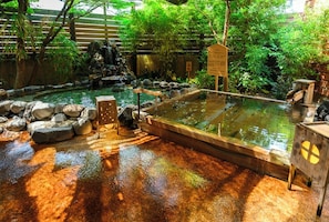 A traditional Japanese onsen with a wooden bath, rocks, and a waterfall. - Wellness Forest Ito Kyoritsu Resort (Ito)