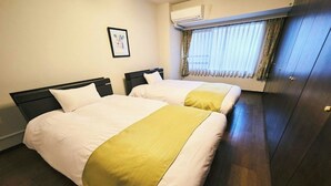 Une chambre d’hôtel avec deux lits, une fenêtre avec des rideaux, un appareil de climatisation et un tableau encadré au mur.