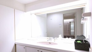 Une salle de bain avec un lavabo blanc, un miroir et des armoires.