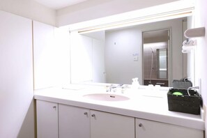 Un baño con un lavamanos blanco, espejo y armarios.