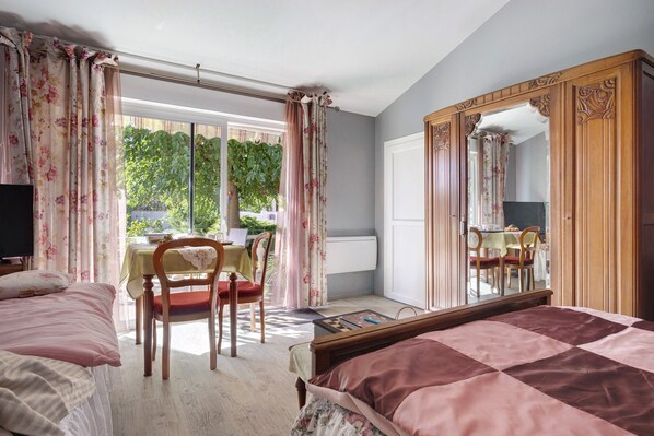 Une chambre à coucher avec un grand lit, une armoire en bois, un bureau avec une chaise et une fenêtre avec des rideaux.