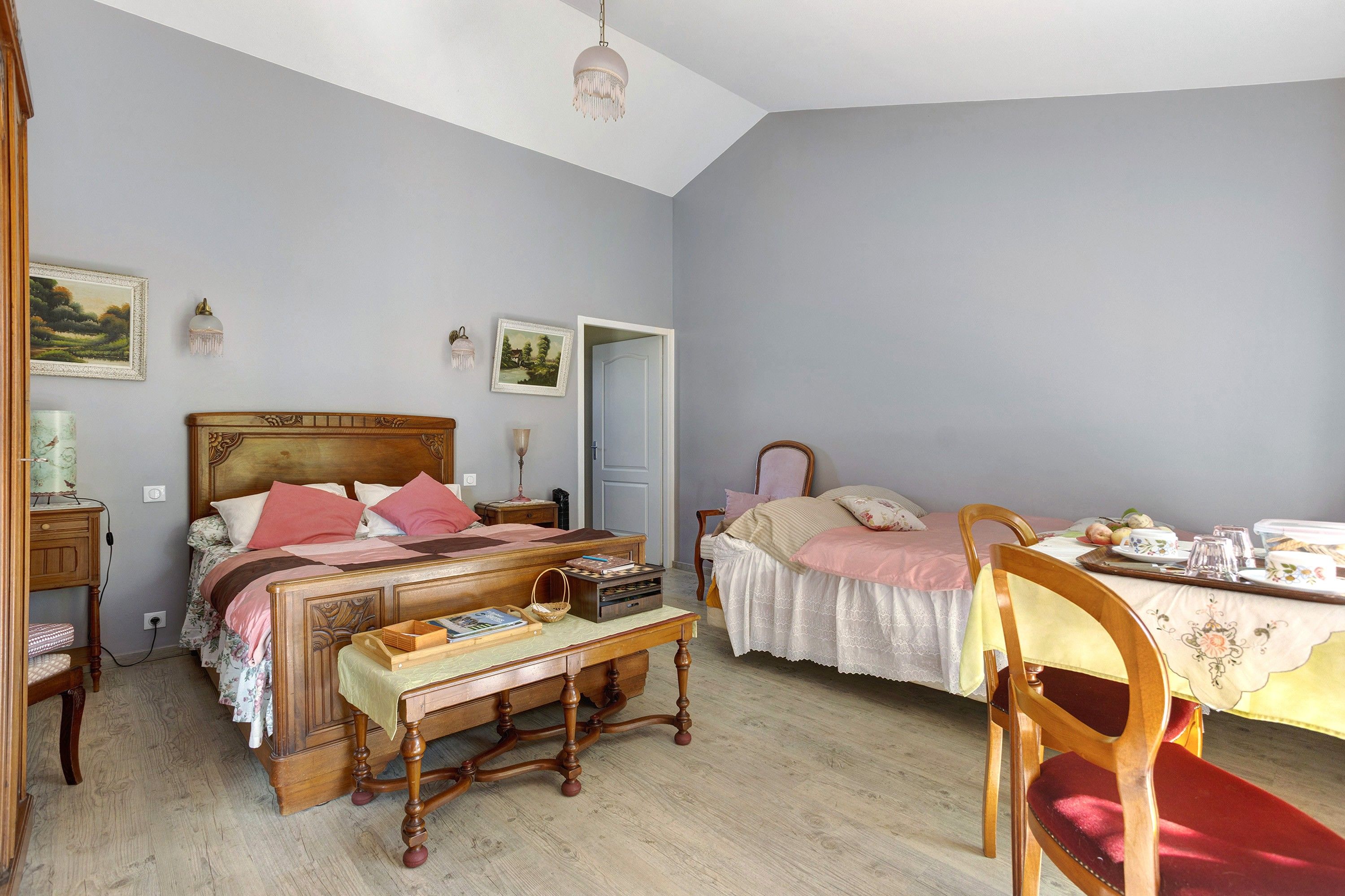 Ein Schlafzimmer mit einem Doppelbett, Nachttischen, einer Holzbank, einem Sessel und einem Esstisch mit Stühlen.