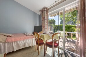 Une chambre à coucher avec un lit, un bureau et une chaise. Il y a une fenêtre avec des rideaux et une vue sur la verdure à l’extérieur.