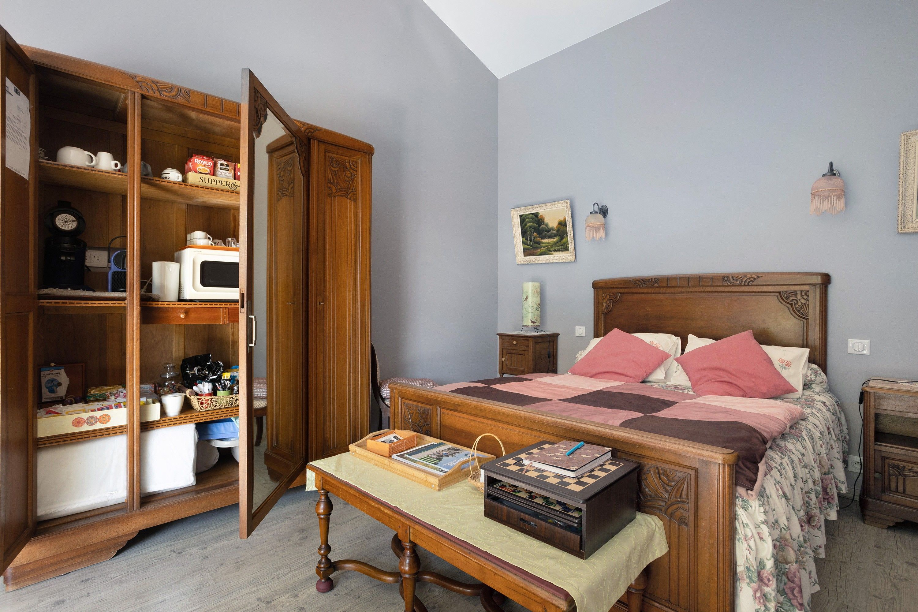 Een slaapkamer met een houten bed, nachtkastje, kapstok en garderobe.