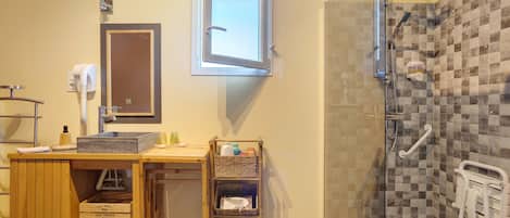 A bathroom with a shower, a sink, a mirror, and a towel rack.