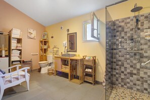 A bathroom with a shower, toilet, and a sink area.