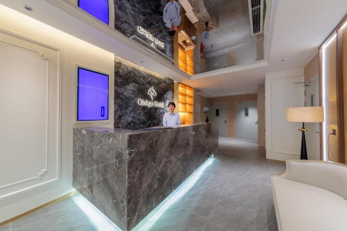 Una reception hotel con un bancone in marmo, uno schermo digitale e un'addetta alla reception.