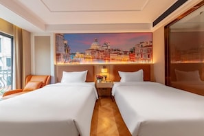 Una camera d'albergo con due letti, un comodino, una lampada e un quadro raffigurante un panorama urbano.