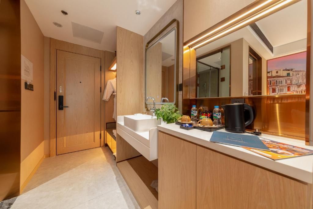 A modern bathroom with a wooden vanity, a large mirror, and a coffee maker on the counter.