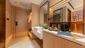 A modern bathroom with a wooden vanity, a large mirror, and a coffee maker on the counter.