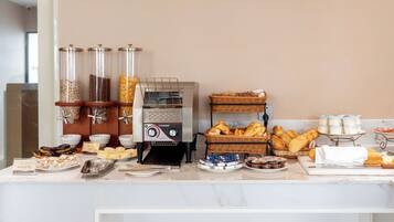 A buffet setup with a coffee machine, various food items, and a tea station.