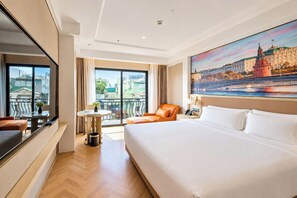 A hotel room with a large bed, a seating area with a table, and a view of a cityscape through the window. - Ginkgo Hotel Hanoi (Hanoi)